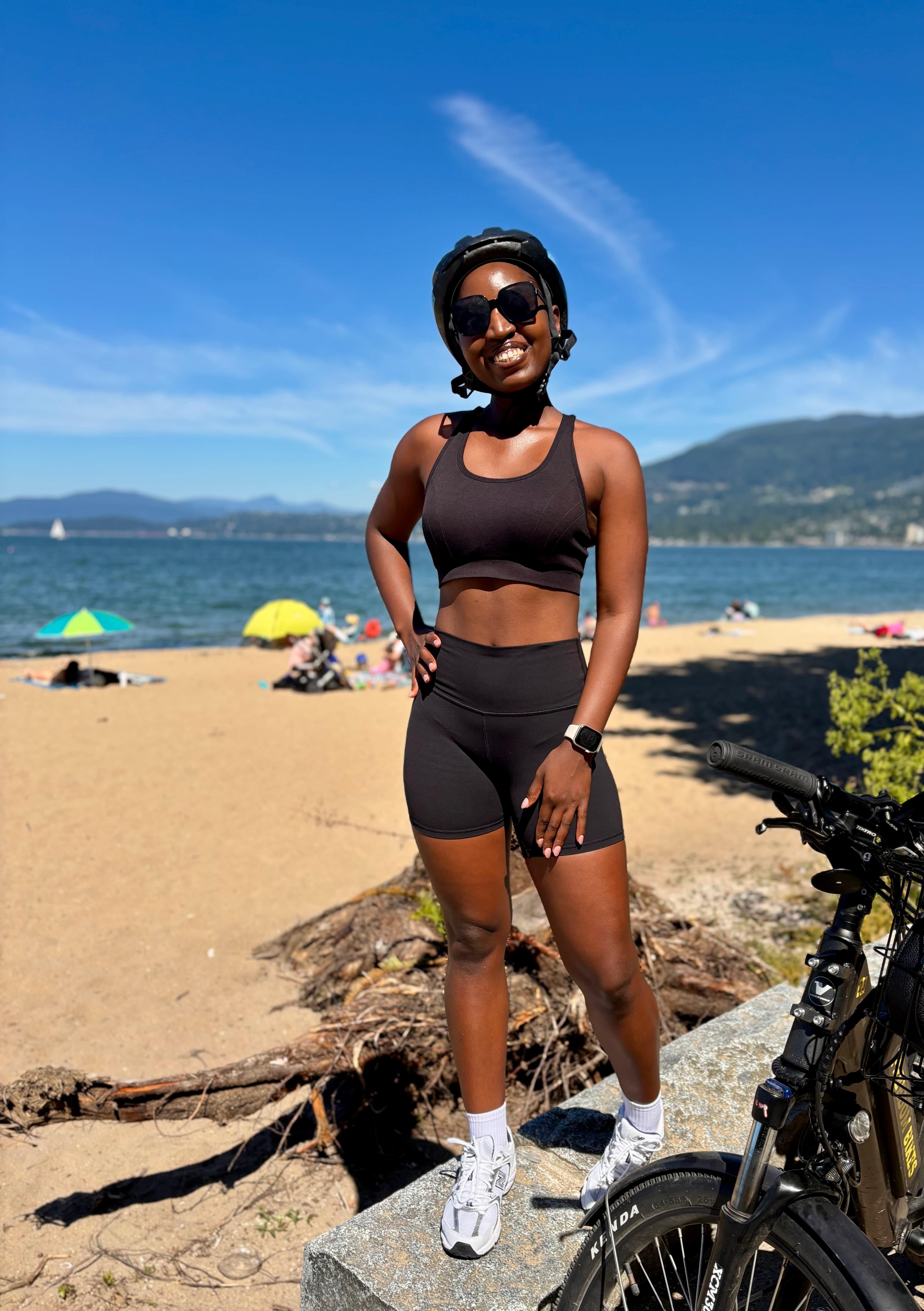 Gloria standing with her bike on a Vancouver beach